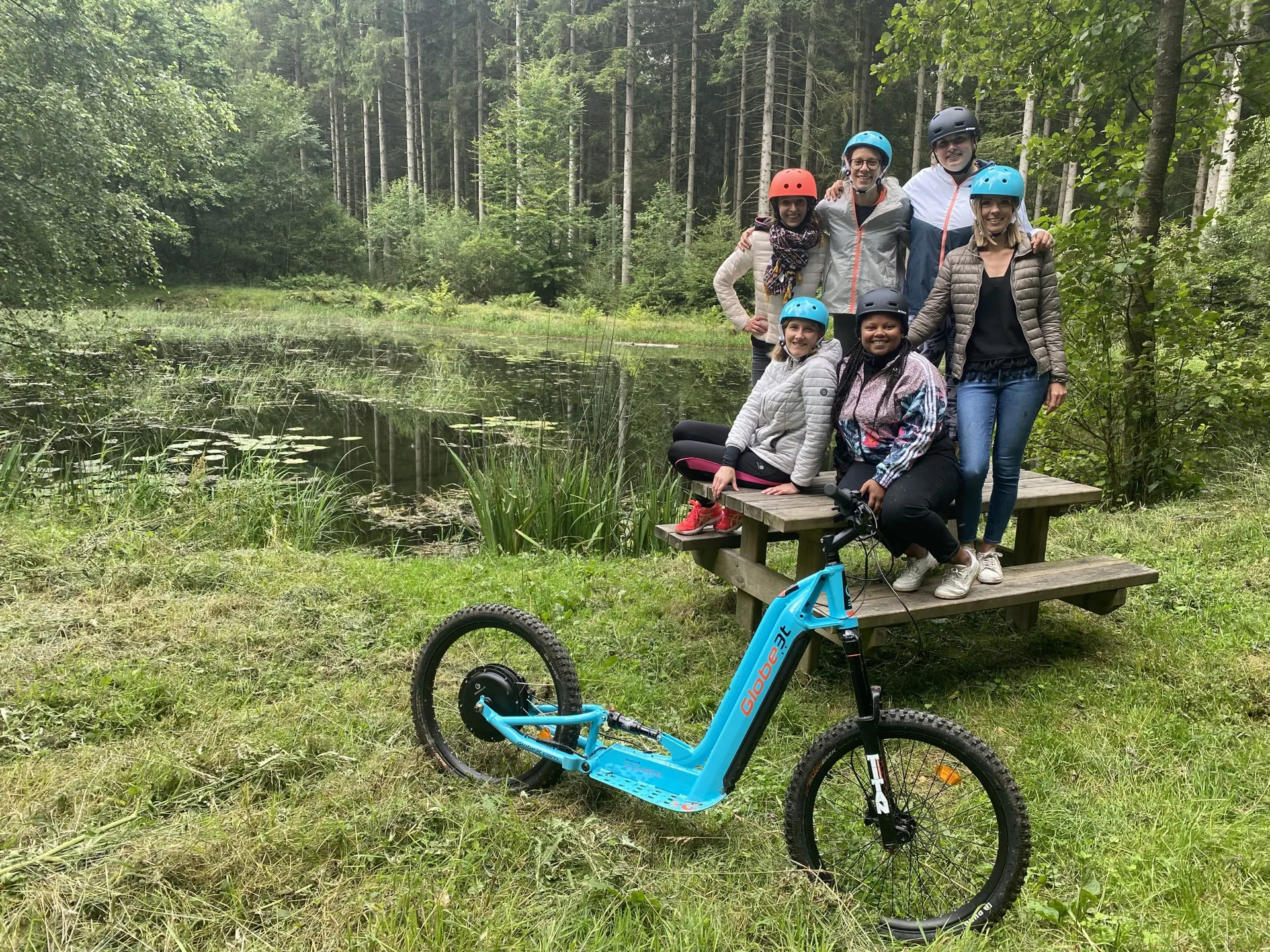 Trottinette électrique tout-terrain I.D. Trotti devant un groupe de randonneurs dans les Ardennes belges à Bastogne.